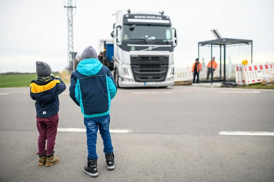 Zwei Kinder beobachten die Errichtung einer Bushaltestelle