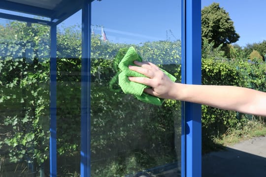 Ein Mann putzt mit Putzlappen die Scheibe