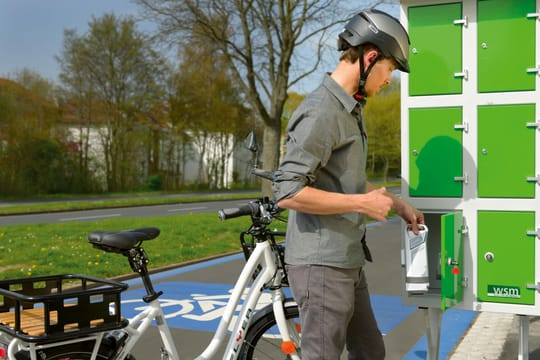 Elektrorad-Fahrer auf einem Radschnellweg vor einem Schließfach