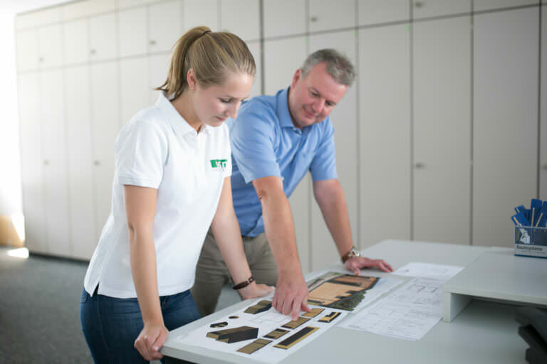 Trainee industrial clerk in front of plans for a room system